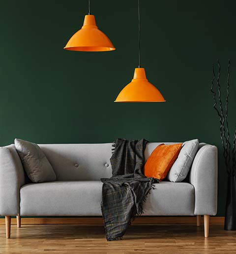 Salón con pared verde, sofá claro y detalles cálidos